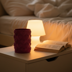 Red Love Hearts vase on a bedside table beside a lamp and open book in a cozy bedroom